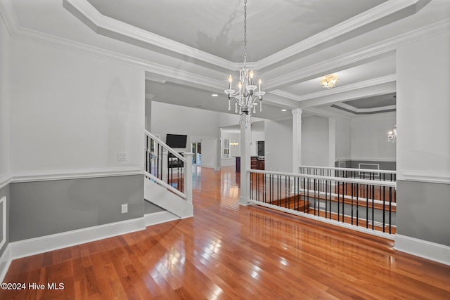 unfurnished room featuring a tray ceiling, crown molding, a chandelier, and wood-type flooring