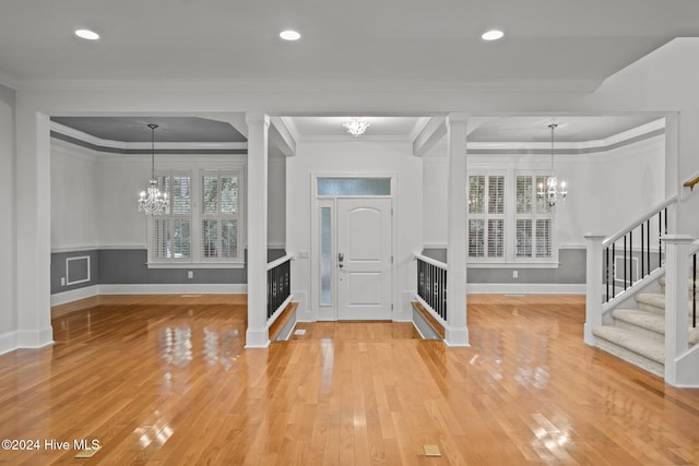 foyer featuring hardwood / wood-style floors, ornate columns, and crown molding