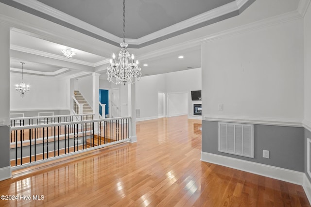 unfurnished room with wood-type flooring, a tray ceiling, and ornamental molding