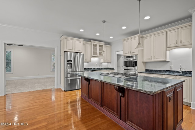 kitchen featuring pendant lighting, dark stone counters, crown molding, sink, and appliances with stainless steel finishes