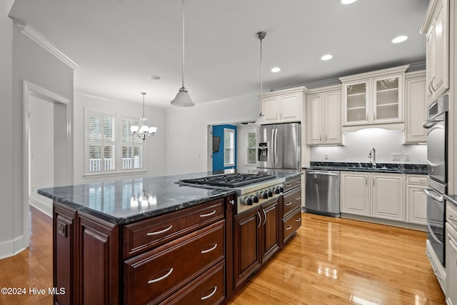 kitchen with stainless steel appliances, a healthy amount of sunlight, dark brown cabinets, and hanging light fixtures