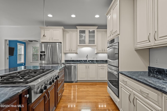 kitchen featuring white cabinetry, stainless steel appliances, crown molding, pendant lighting, and light wood-type flooring