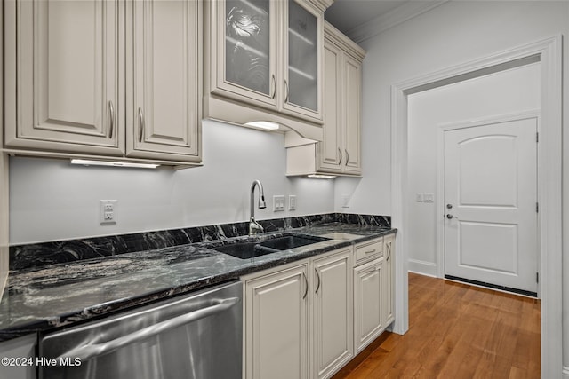 kitchen featuring dishwasher, dark stone counters, sink, crown molding, and light hardwood / wood-style floors