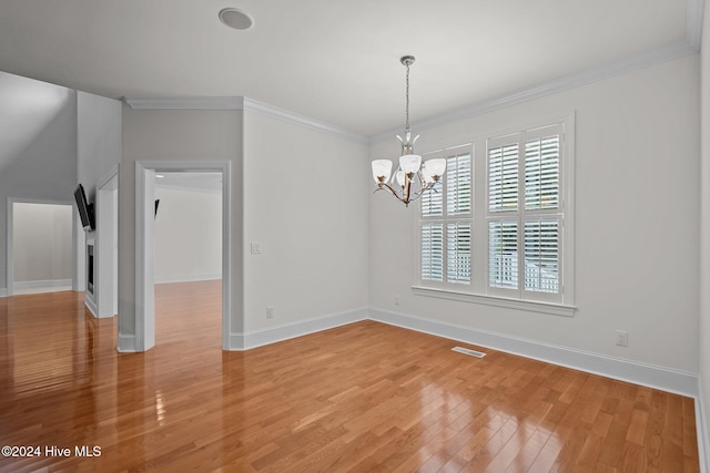 empty room with a notable chandelier, wood-type flooring, and ornamental molding