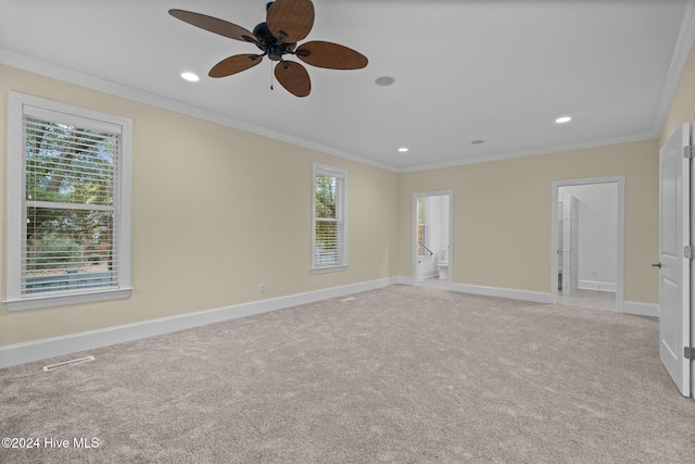 carpeted spare room featuring ceiling fan, a healthy amount of sunlight, and ornamental molding