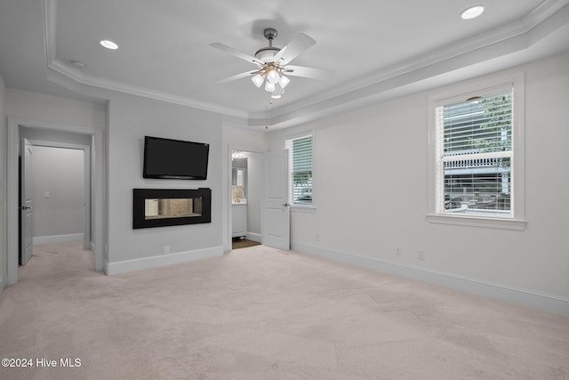 unfurnished living room featuring light carpet, a multi sided fireplace, a tray ceiling, and crown molding