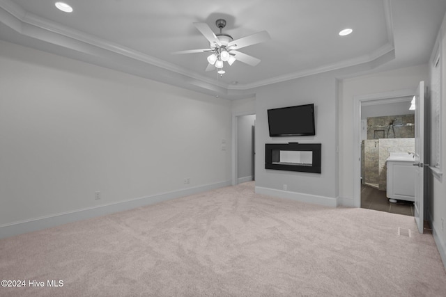 unfurnished living room with carpet, a tray ceiling, ceiling fan, and ornamental molding