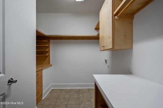 clothes washing area featuring cabinets, light tile patterned floors, and washer hookup