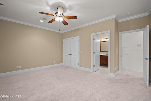 unfurnished bedroom featuring ceiling fan, ensuite bathroom, light colored carpet, a closet, and ornamental molding