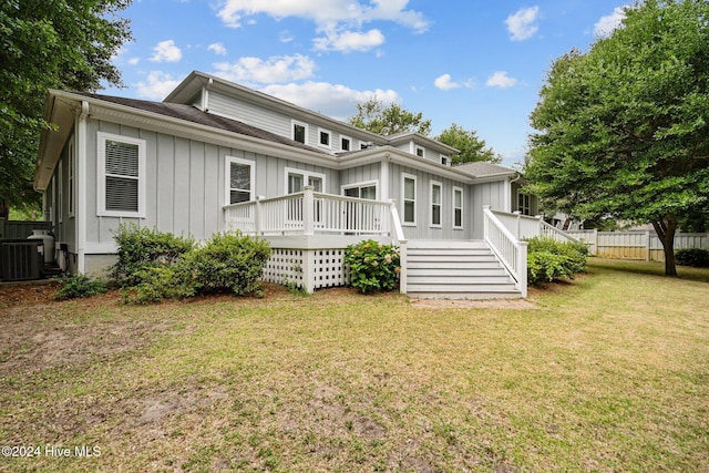 rear view of property with a yard, a wooden deck, and central AC