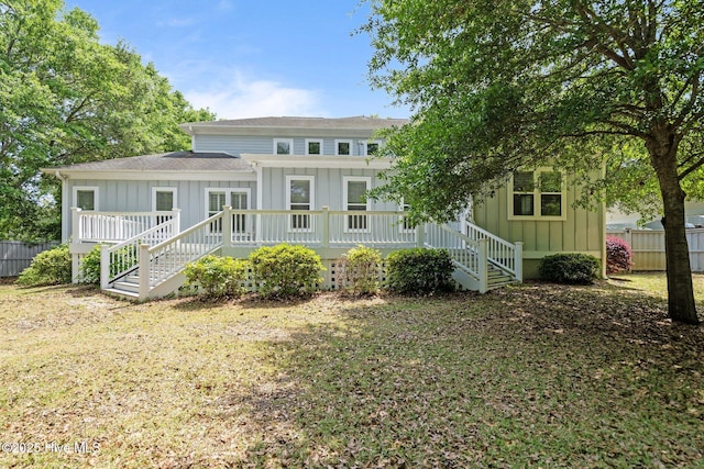 rear view of property featuring a shingled roof, board and batten siding, and fence