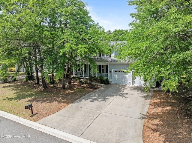 obstructed view of property featuring an attached garage, board and batten siding, driveway, and a porch