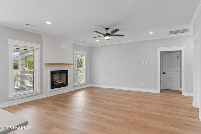 457 Raven Glen Dr, Southport, NC 28461 - unfurnished living room featuring crown molding, light wood-style floors, a large fireplace, a ceiling fan, and baseboards