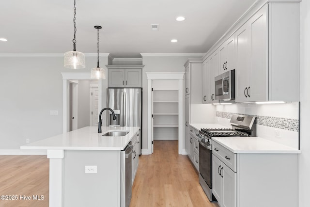 457 Raven Glen Dr, Southport, NC 28461 - kitchen featuring stainless steel appliances, a sink, crown molding, a center island with sink, and light wood-style flooring