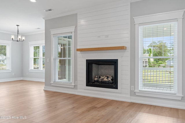 457 Raven Glen Dr, Southport, NC 28461 - unfurnished living room with ornamental molding, a chandelier, light wood finished floors, baseboards, and a fireplace