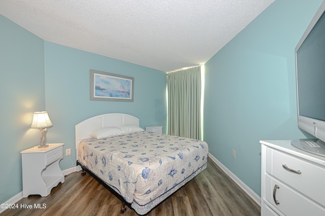 bedroom featuring a textured ceiling and dark wood-type flooring