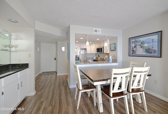 dining space featuring hardwood / wood-style floors and a textured ceiling