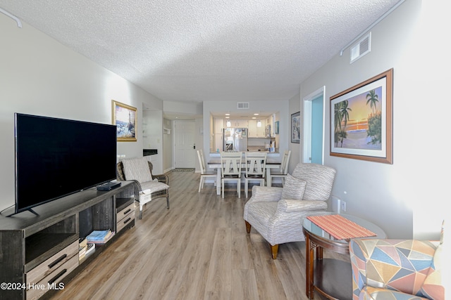 living room with light hardwood / wood-style floors and a textured ceiling