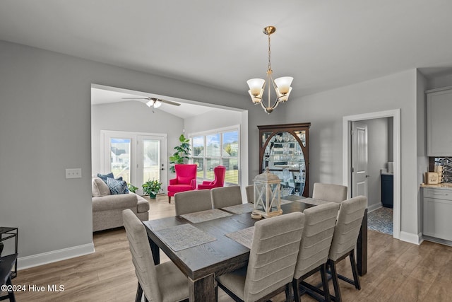 dining area featuring ceiling fan with notable chandelier, light hardwood / wood-style floors, and vaulted ceiling