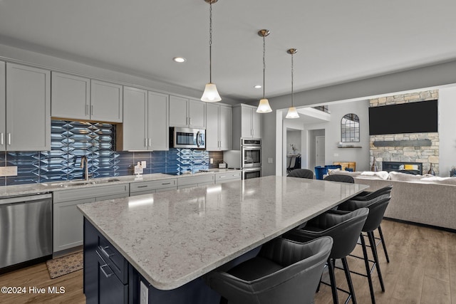 kitchen featuring hardwood / wood-style floors, sink, a fireplace, decorative light fixtures, and stainless steel appliances