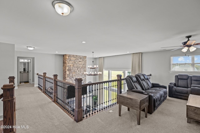 living room with ceiling fan with notable chandelier and light colored carpet