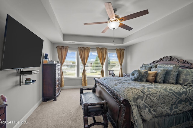 bedroom featuring a tray ceiling, ceiling fan, and light carpet