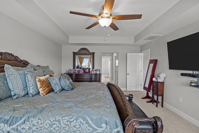 carpeted bedroom featuring ceiling fan and a raised ceiling