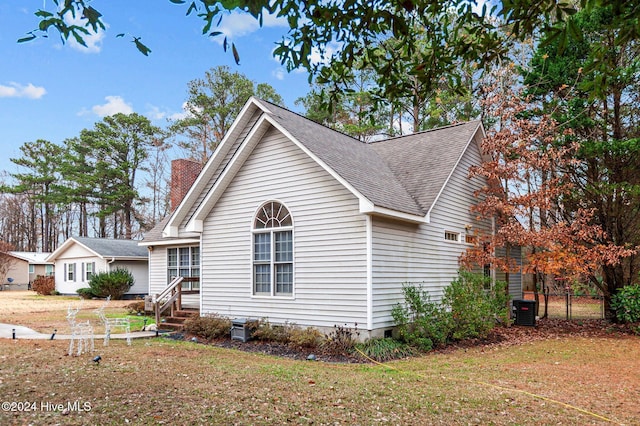 view of side of property with central air condition unit and a lawn