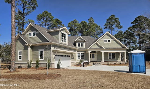 craftsman inspired home featuring a shingled roof, a porch, and concrete driveway