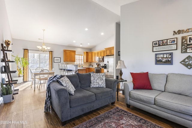 living room with a notable chandelier, wood-type flooring, and high vaulted ceiling