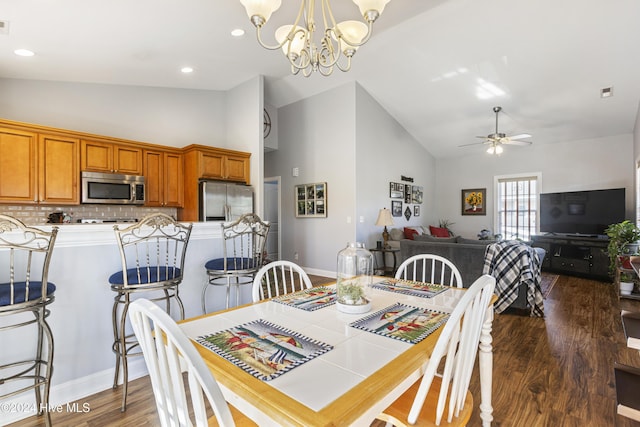 dining space with dark hardwood / wood-style flooring, high vaulted ceiling, and ceiling fan with notable chandelier