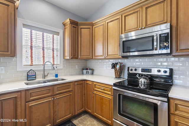 kitchen featuring decorative backsplash, sink, appliances with stainless steel finishes, and vaulted ceiling