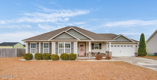 craftsman inspired home featuring covered porch, central AC unit, and a garage