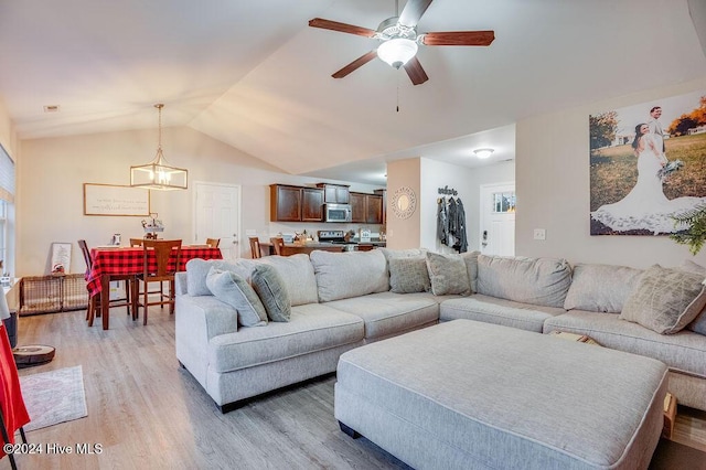 living room featuring ceiling fan with notable chandelier, light hardwood / wood-style floors, and lofted ceiling