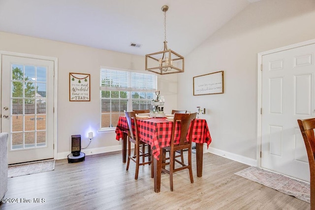 dining area featuring hardwood / wood-style flooring, plenty of natural light, a chandelier, and vaulted ceiling