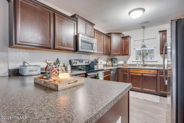 kitchen with sink, hanging light fixtures, dark brown cabinets, and appliances with stainless steel finishes