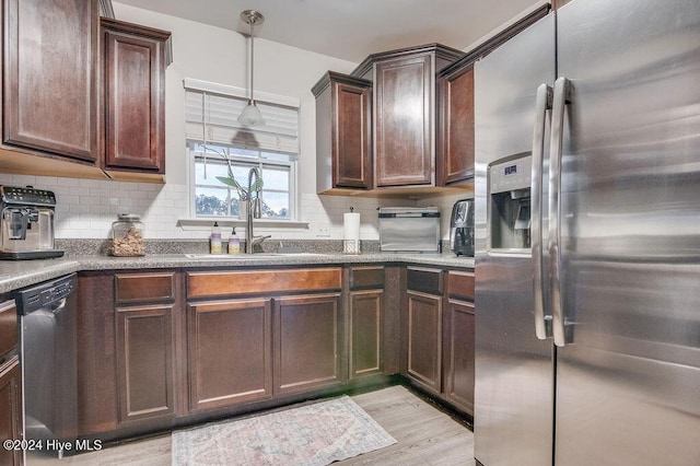 kitchen featuring decorative light fixtures, light hardwood / wood-style floors, appliances with stainless steel finishes, and tasteful backsplash