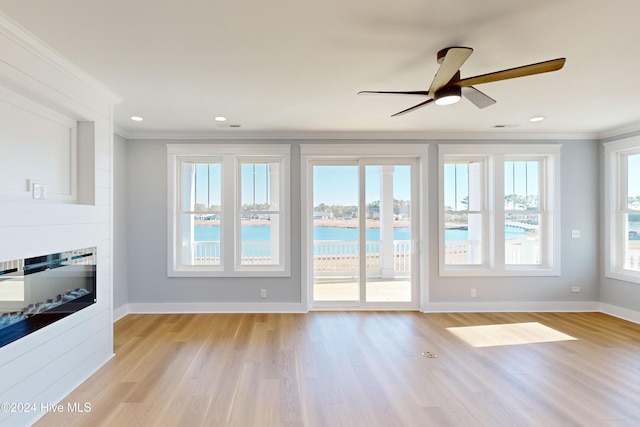 interior space with light hardwood / wood-style floors, ceiling fan, crown molding, and a water view