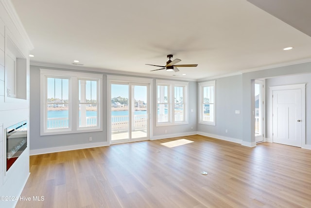 unfurnished living room featuring ceiling fan, a water view, ornamental molding, and light hardwood / wood-style flooring