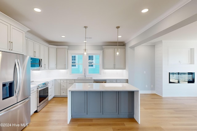 kitchen with appliances with stainless steel finishes, light hardwood / wood-style floors, hanging light fixtures, and sink