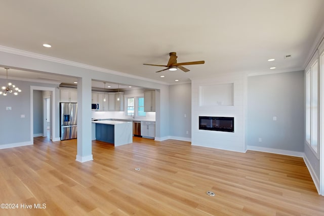 unfurnished living room with a fireplace, ceiling fan with notable chandelier, light hardwood / wood-style floors, and ornamental molding