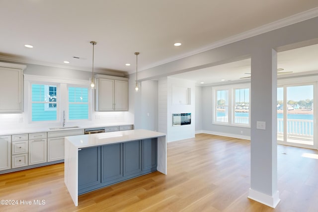 kitchen with sink, light hardwood / wood-style flooring, ceiling fan, ornamental molding, and decorative light fixtures