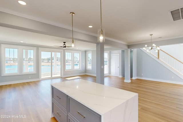 kitchen featuring light stone countertops, hanging light fixtures, light hardwood / wood-style flooring, crown molding, and ceiling fan with notable chandelier