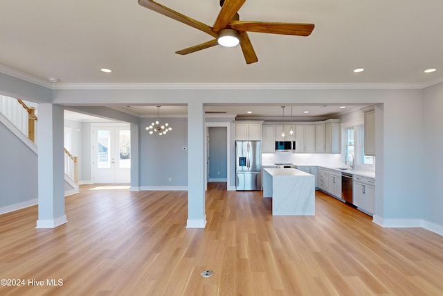 kitchen with appliances with stainless steel finishes, decorative light fixtures, light hardwood / wood-style flooring, and sink