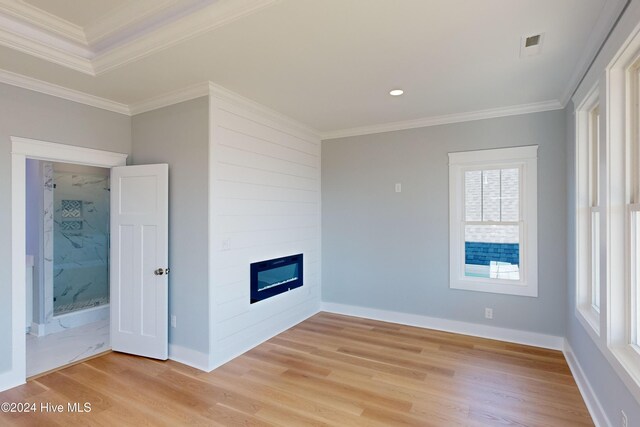 unfurnished living room featuring a large fireplace, light hardwood / wood-style floors, and ornamental molding