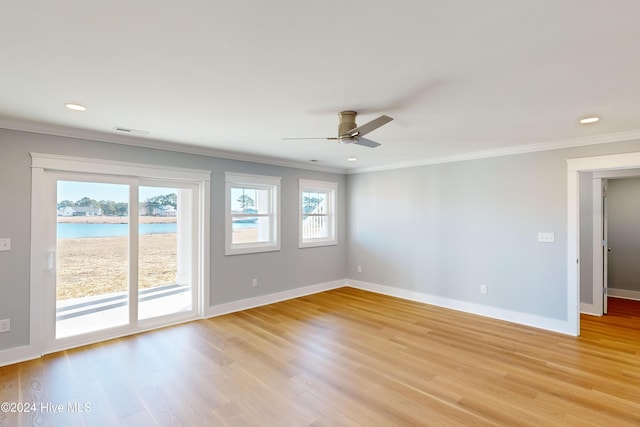 empty room with ceiling fan, light hardwood / wood-style flooring, a water view, and ornamental molding