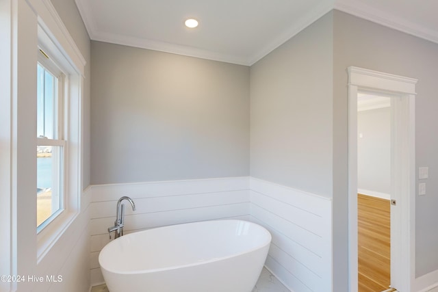 bathroom featuring ornamental molding, hardwood / wood-style flooring, tile walls, and a bathing tub