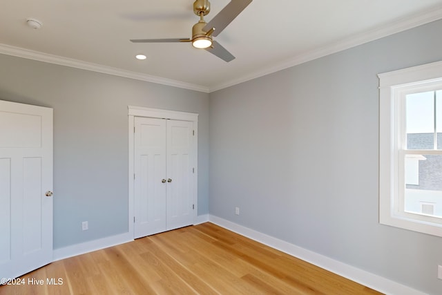 unfurnished bedroom with hardwood / wood-style floors, ceiling fan, crown molding, and a closet