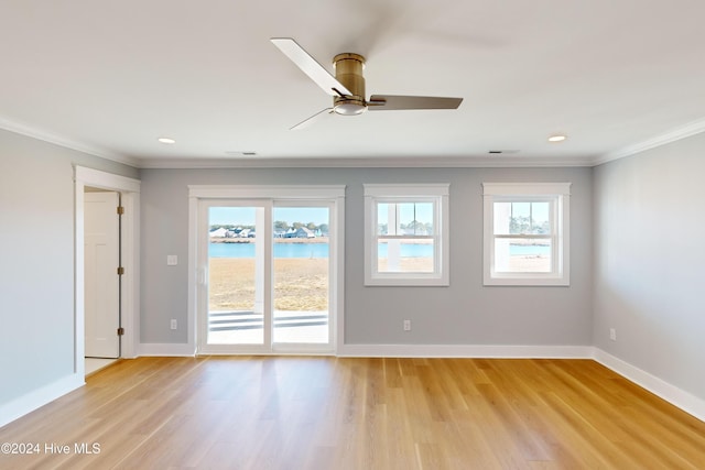 empty room with a wealth of natural light, crown molding, ceiling fan, and light wood-type flooring