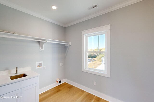 laundry room featuring cabinets, crown molding, sink, hookup for a washing machine, and light hardwood / wood-style floors